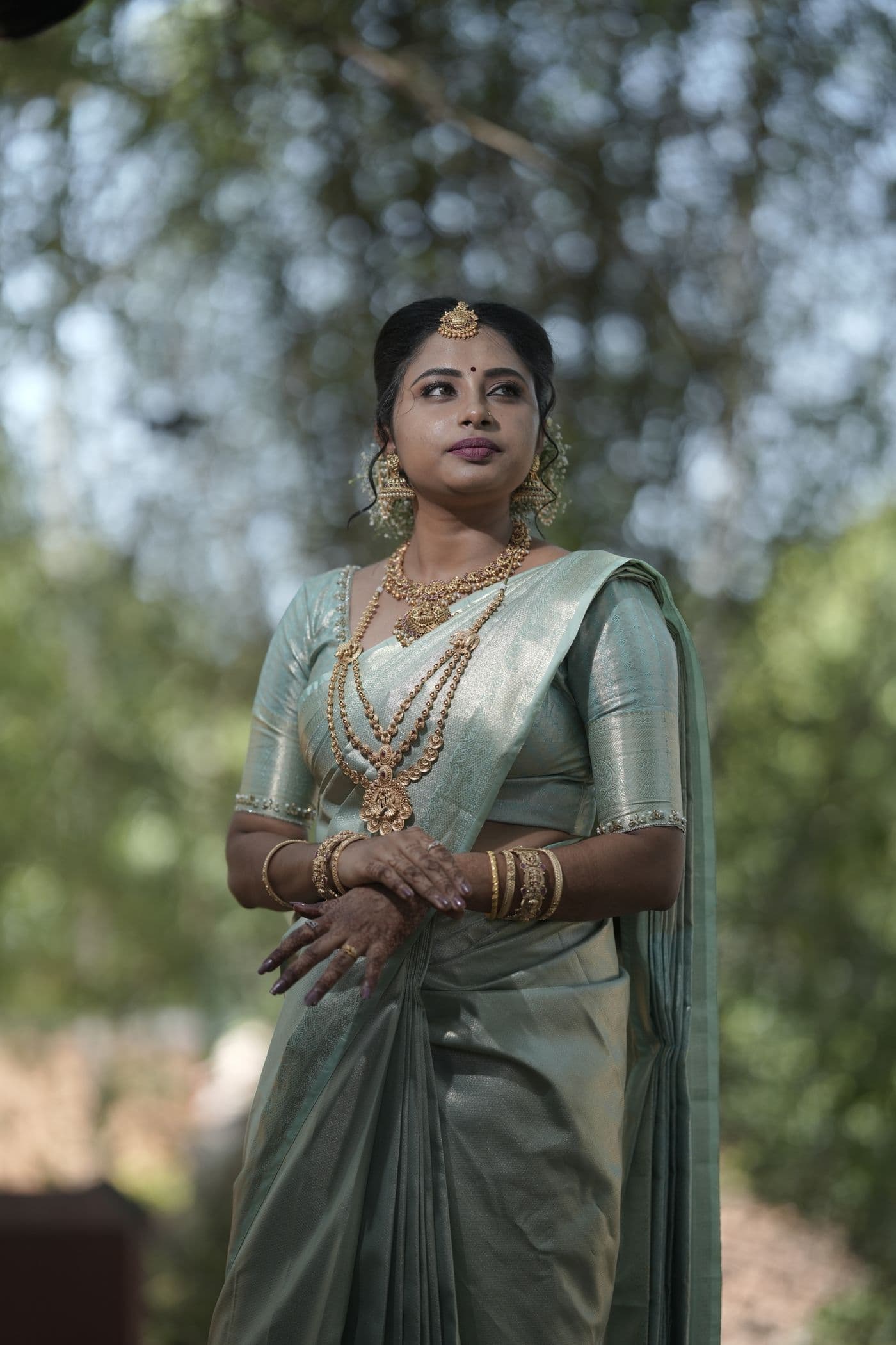 Woman in a pale silk saree outdoors in soft light