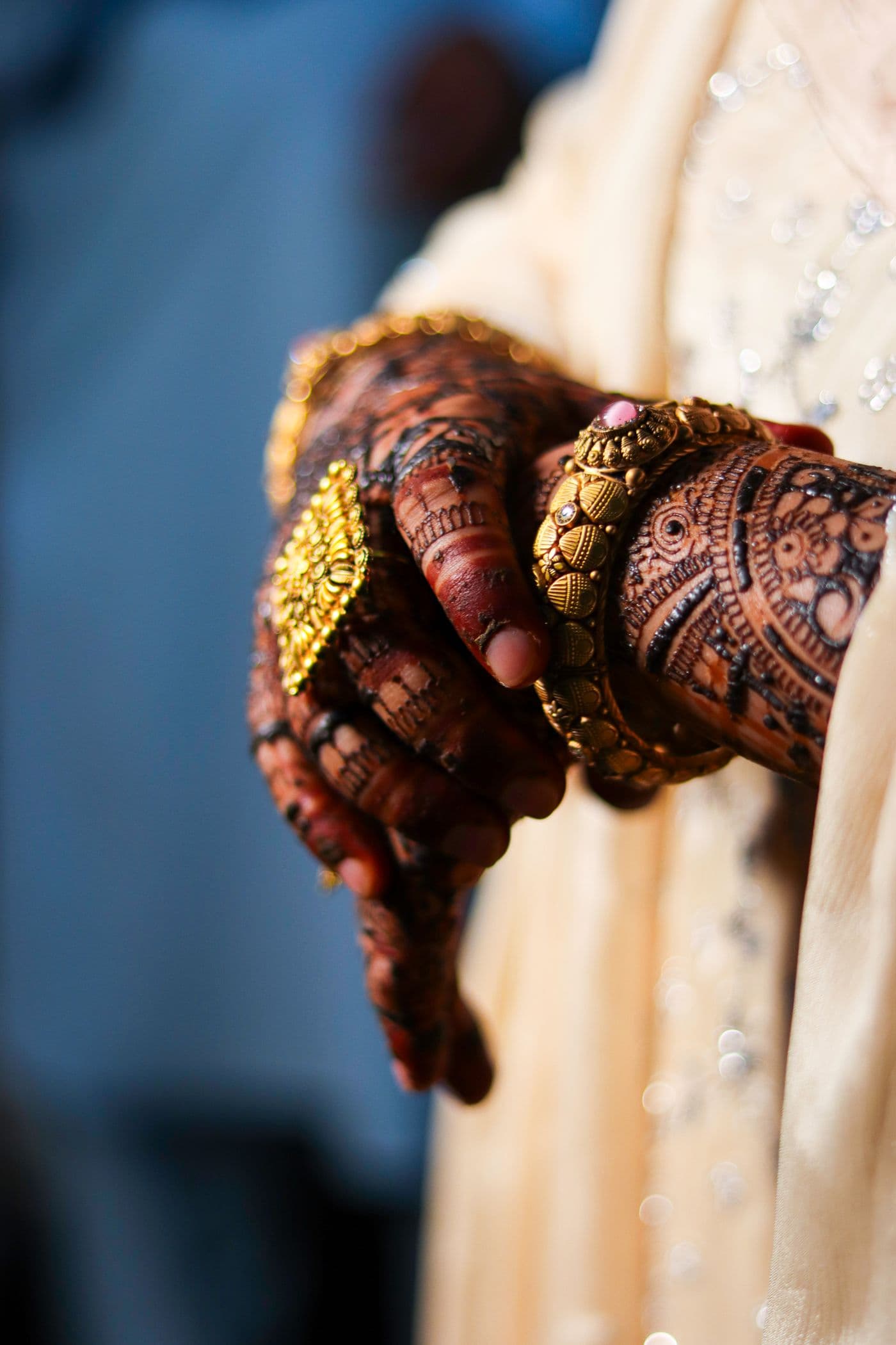 Bride's henna-adorned hands resting over gold bangles and jewellery