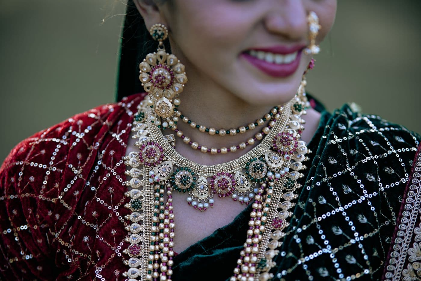 Close-up of layered gold and pearl bridal jewellery on dark fabric