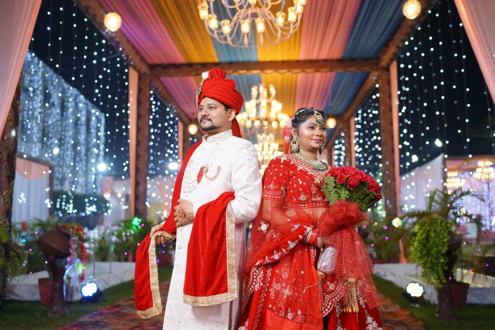 Couple in traditional wedding attire at a vibrant night celebration