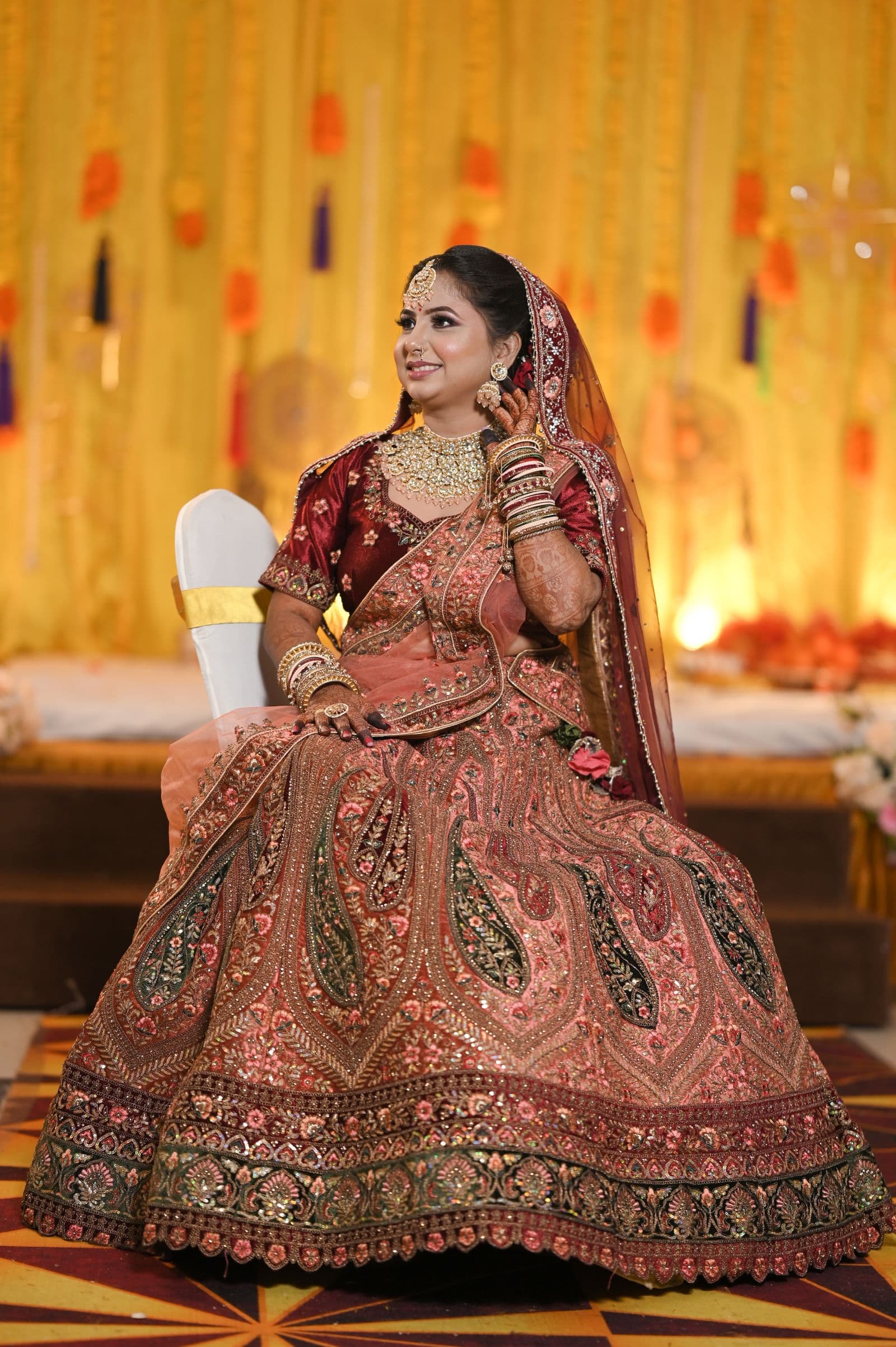 Bride seated in an intricately embroidered red and gold lehenga