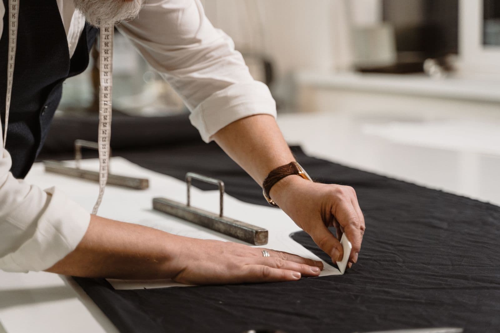 Tailor's hands marking fabric with chalk in the atelier
