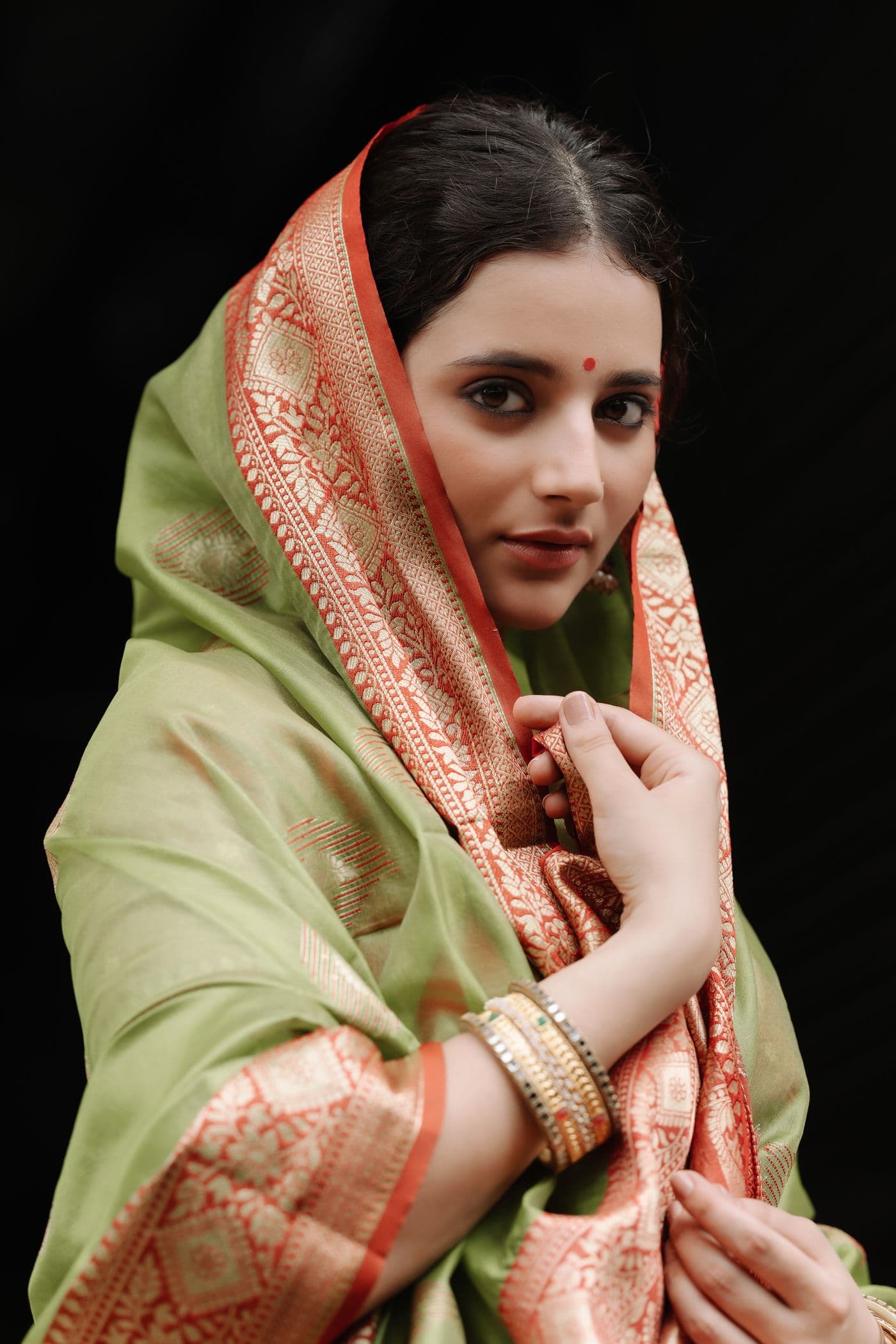 Woman in a soft green veil holding the fabric close