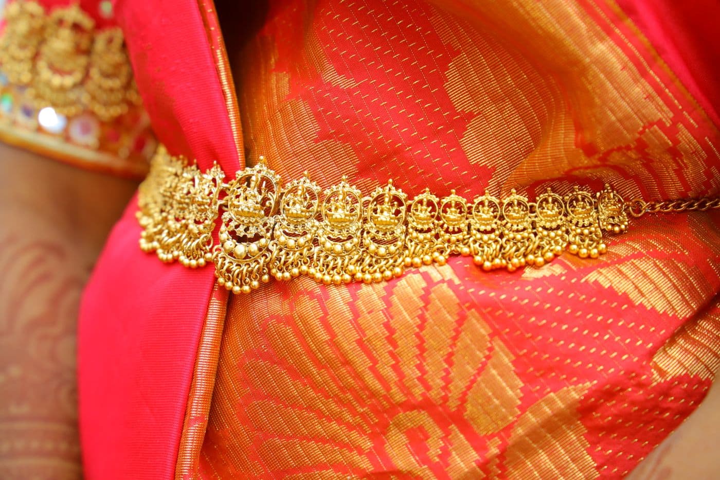Close-up of a gold embroidered waist belt over vivid sari fabric